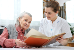elderly woman with her caregiver reading a book